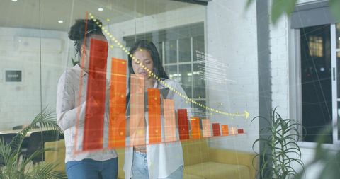 Female Business Analysts Viewing Digital Financial Charts in Modern Office
