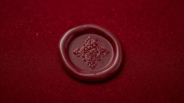 Intricate floral wax seal on rich red felt background