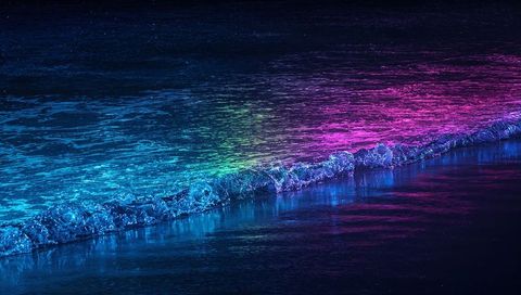 Neon ocean wave reflecting cyan to purple light on night beach with iridescent foam