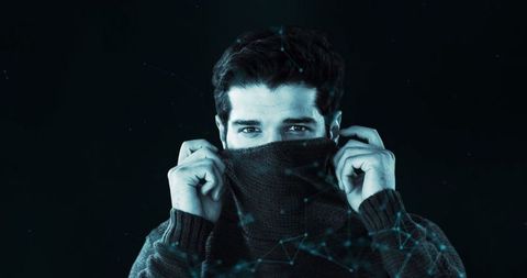 Mysterious man hiding face with collar in low light