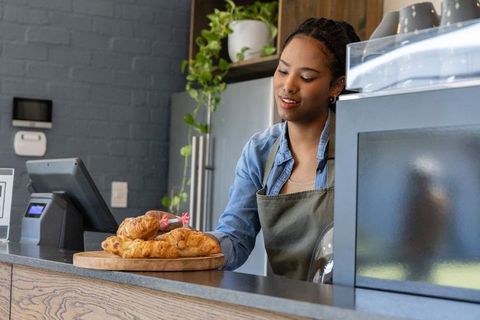 African american barista arranging fresh croissants at café counter