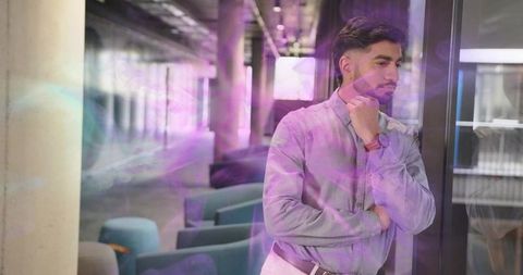 Reflective businessman leans against office glass in modern corporate lounge