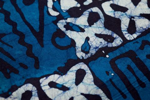 Close-up showing indigo batik textile with cracked resist lines and abstract motifs