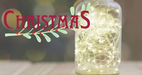 Glowing christmas jar lights with warm bokeh and festive red lettering on wood surface