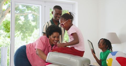 Happy African American Family Packing for Vacation at Home Together