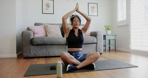 Woman meditating on yoga mat in bright living room practicing mindfulness and home wellness