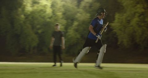 Cricket batsman sprinting for quick run under floodlights during competitive night match
