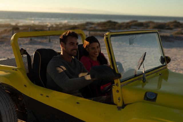 Happy caucasian couple driving in beach buggy by the sea at sunset, smiling. beach stop off on romantic summer holiday road trip.