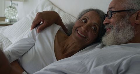 Happy Biracial Seniors Relaxing in Cozy Bedroom