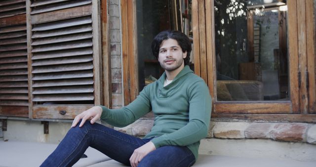 Young Man Relaxing Outdoors Wearing Green Sweater and Jeans - Download Free Stock Images Pikwizard.com