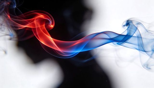 Flowing red and blue smoke ribbon twisting fluid across high-contrast black white backdrop