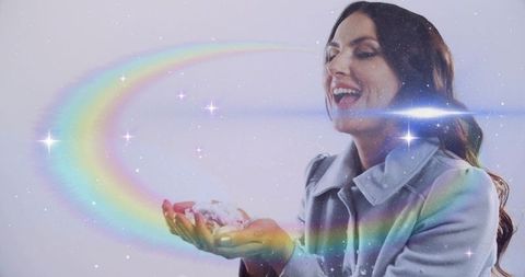 Smiling woman holding glitter snow while rainbow arc and stars swirl around