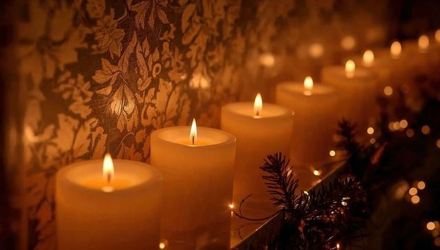 Amber pillar candlelight lining mantel with damask wallpaper and festive garland bokeh