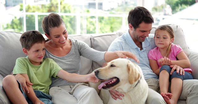 Cute family relaxing together on the couch with their labrador dog in living room at home