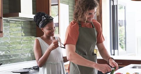 Diverse Couple Joyfully Cooking Together in Bright Modern Kitchen