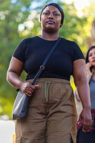 Confident african woman walking wearing headscarf with crossbody bag, urban lifestyle