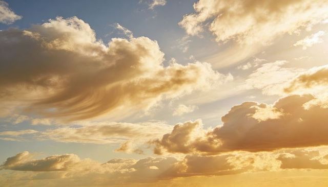 Glowing clouds casting golden sunbeams over coastal horizon, sunrise illuminating sea