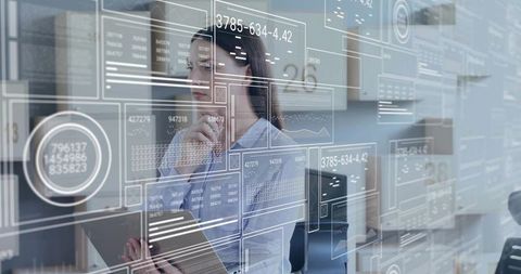 Female analyst interacting with augmented data interface holding tablet in modern office