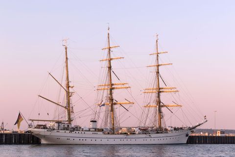 Elegant tall ship anchored at sunset by harbor