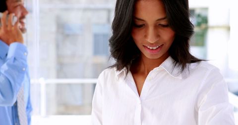 Businesswoman Smiling While Using Smart Watch in Office