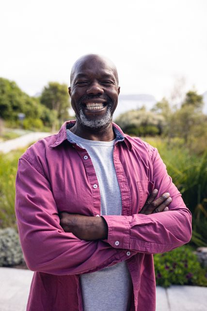 Vertical image of happy african american man smiling at camera. Lifestyle, spending free time at home and garden concept.