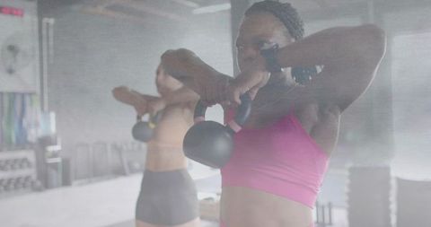 Women lifting kettlebells in industrial gym during functional strength training session