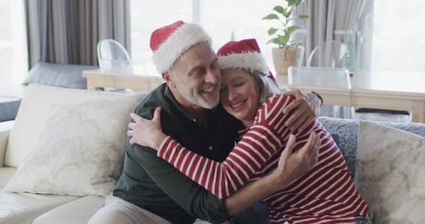 Middle-aged couple embracing in santa hats for christmas