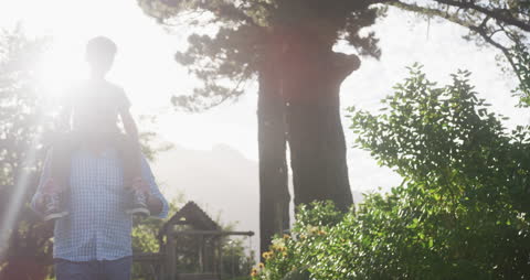 Grandfather Giving Grandson Ride on Shoulders in Sunlit Garden