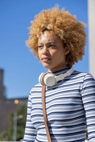 Confident african american woman with headphones and striped top in urban portrait