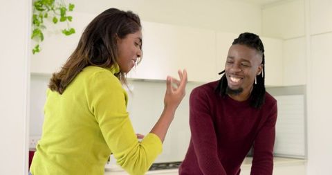Diverse young couple laughing and chatting at bright modern kitchen countertop minimalist interior