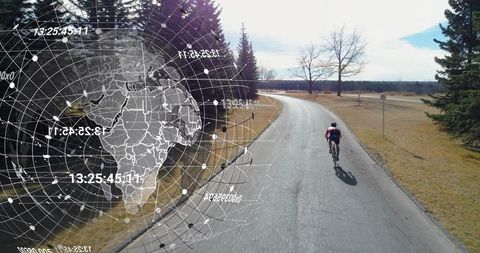 Solo cyclist riding country road with digital globe data overlay for connected fitness