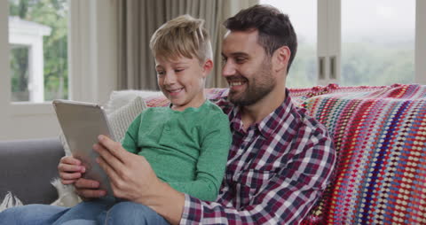 Father and Son Enjoying Time Together with Tablet on Home Sofa