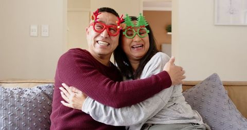 Couple Wearing Fun Christmas Glasses Hugging Joyfully