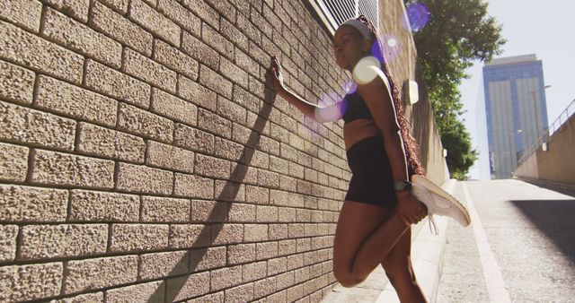 African american woman exercising outdoors leaning of wall and stretching in the city. healthy outdoor lifestyle fitness training.