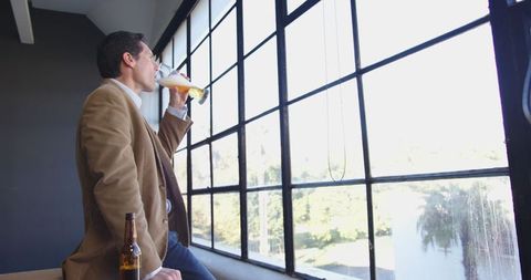 Businessman enjoying beer in modern office setting