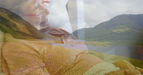 Double exposure senior woman relaxing with highland landscape overlay, serene aging