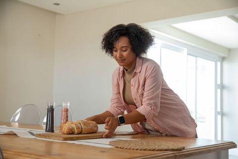 Woman preparing fresh bread at home using wooden cutting board