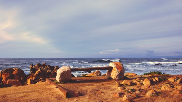 Serene Coastal Sunset with Rocks and Wooden Bench - Download Free Stock Images Pikwizard.com