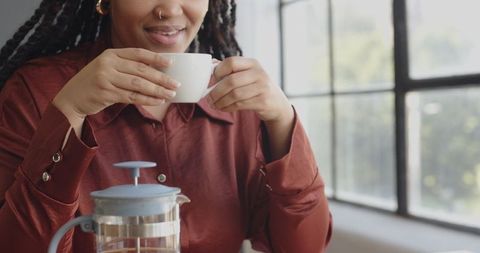 Woman Smiling While Enjoying Coffee At Work