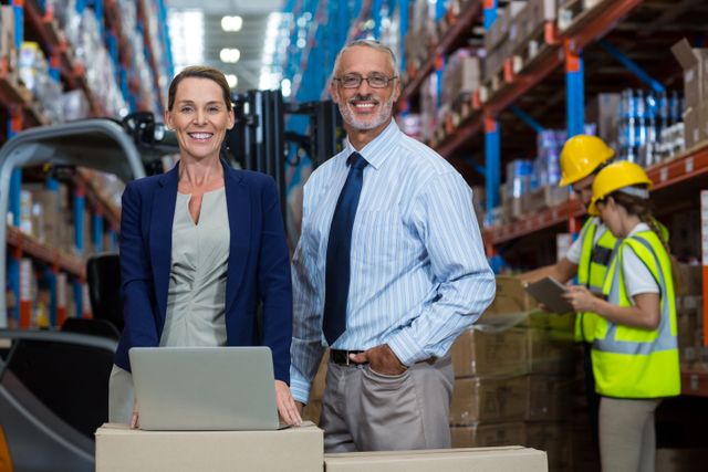 Portrait of warehouse manager and client standing with laptop in warehouse