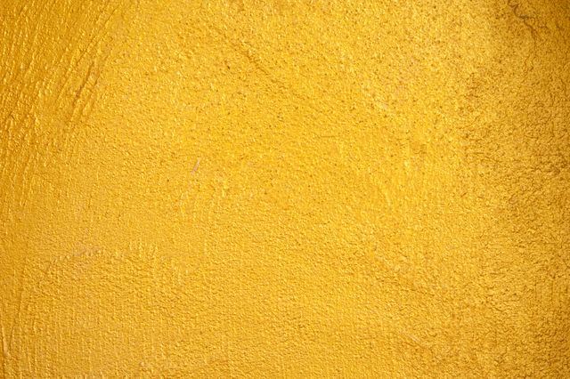 Bright and vibrant yellow wall with a textured surface, suitable as a background for various design projects. Perfect for use in website headers, blog posts, marketing materials, and presentations that require an energetic and warm backdrop. Ideal for highlighting text or graphics with high contrast.
