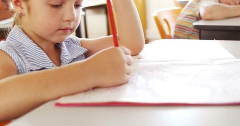 Young Schoolgirl Engaged in Writing Activity in Classroom
