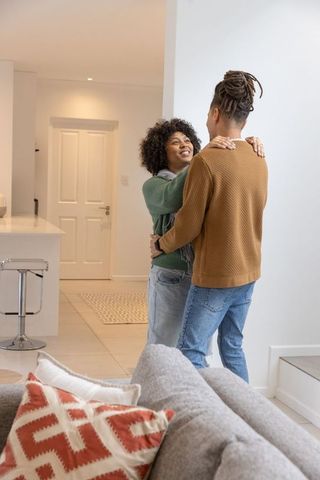African american couple embracing in modern open-plan apartment showing cozy home romance