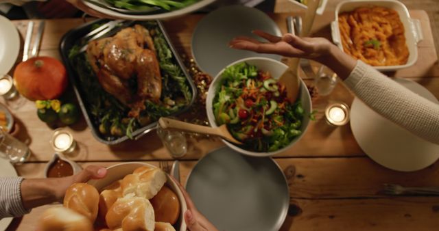 Family hands serving Thanksgiving dinner at home, with copy space. A festive table showcases a variety of traditional dishes.