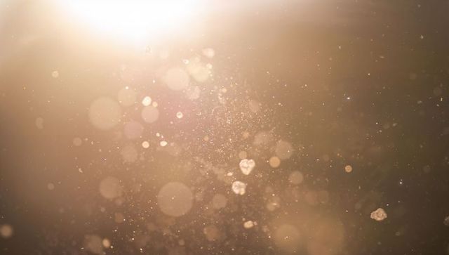 Warm golden dust bokeh drifting through sunlit glow, abstract glitter particles and shimmer backgrou