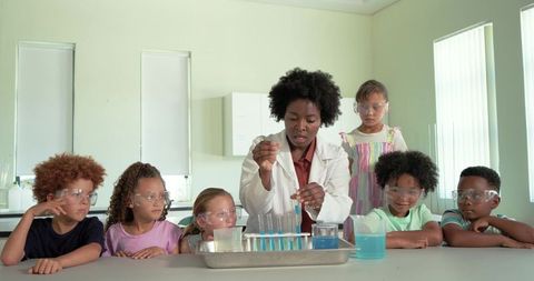 Leading hands-on science experiment with african american teacher and children in goggles