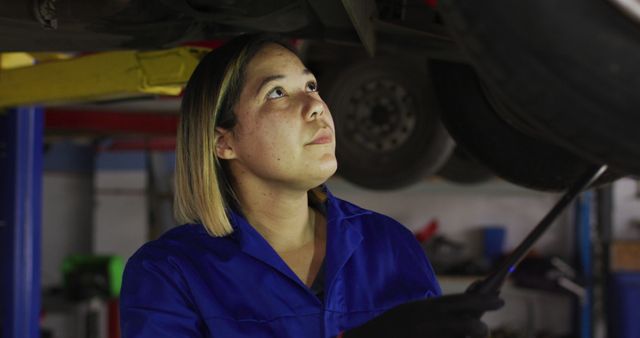 Female mechanic working under a car at a car service station. automobile repair service concept