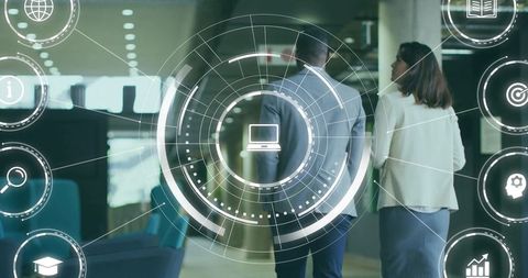 Business professionals walking through modern office with digital HUD laptop interface