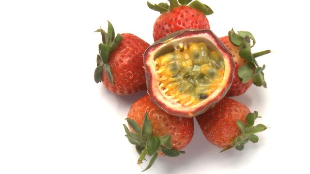 Displayed here is a juicy passion fruit paired with ripe strawberries on a clean white background. This vibrant and colorful arrangement showcases fresh tropical fruits, ideal for topics related to health, nutrition, and delicious superfoods. Perfect for use in food blogs, nutritional guides, or marketing for fresh produce.