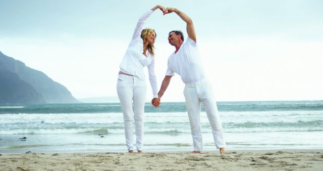 Happy caucasian mature couple holding hands and smiling on beach on winter day. Winter, relax, togetherness and lifestyle,happiness, unaltered.